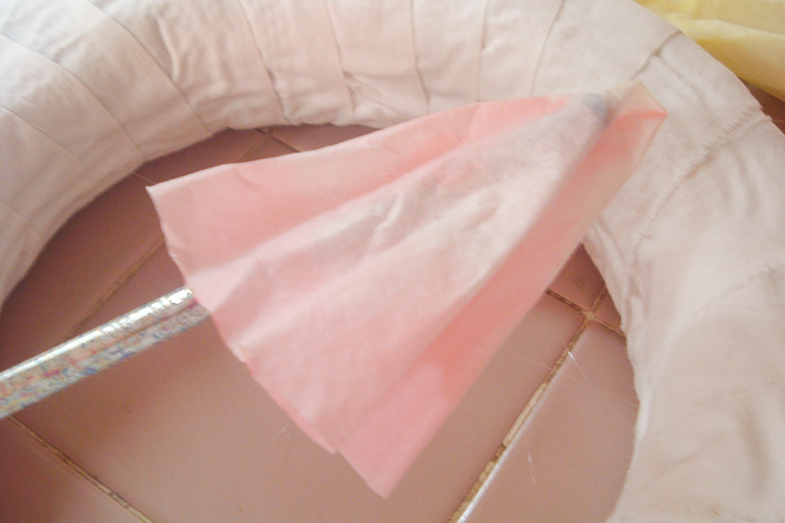 attaching colored coffee filters to wreath form using hot glue